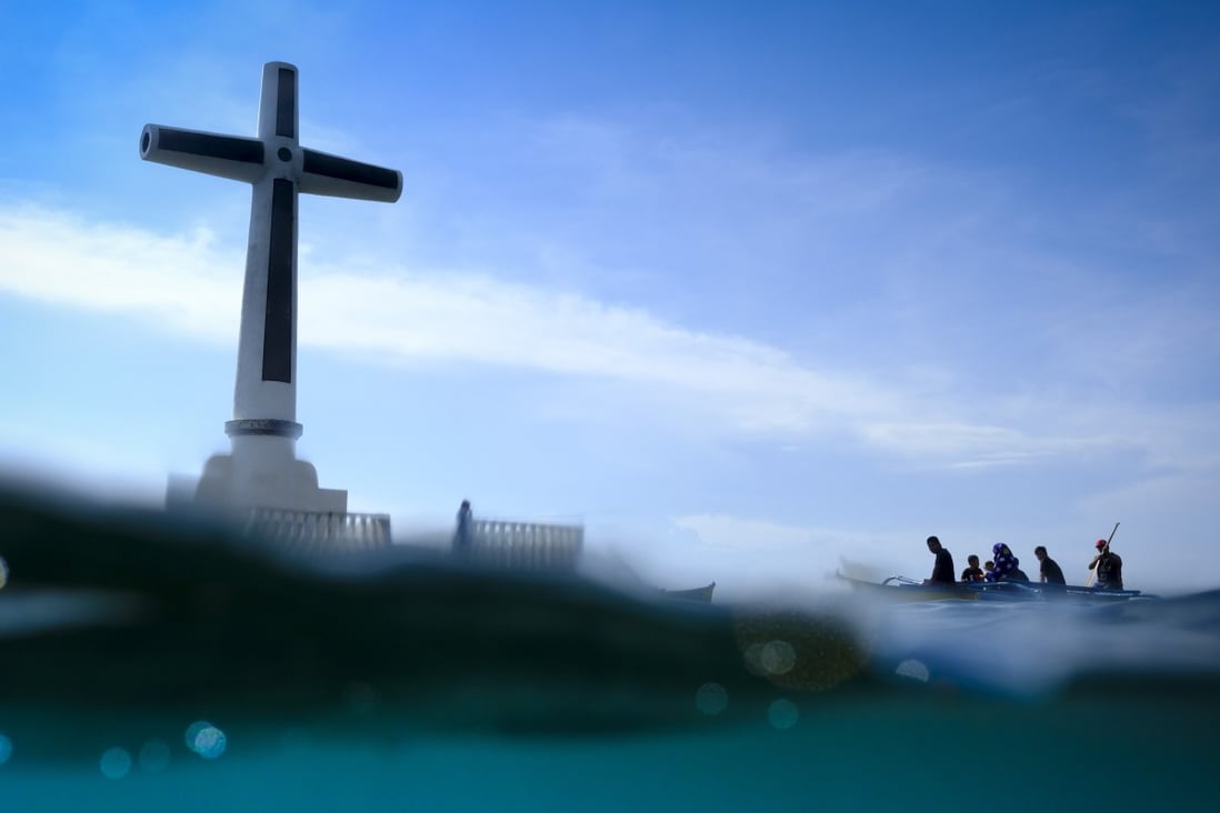 A family whose ancestor is entombed there visit the sunken cemetery in Camiguin, engulfed following a volcanic eruption in 1871. Photo: James Wendlinger