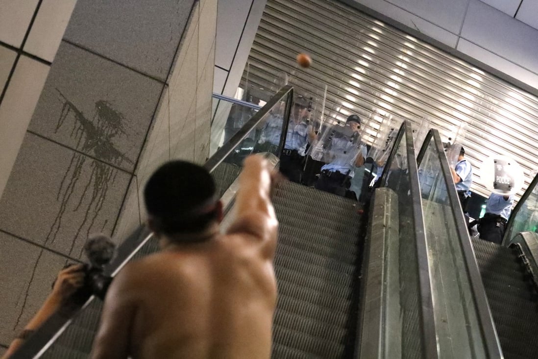 A protester throws an egg at officers at the police headquarters in Wan Chai. Photo: Felix Wong