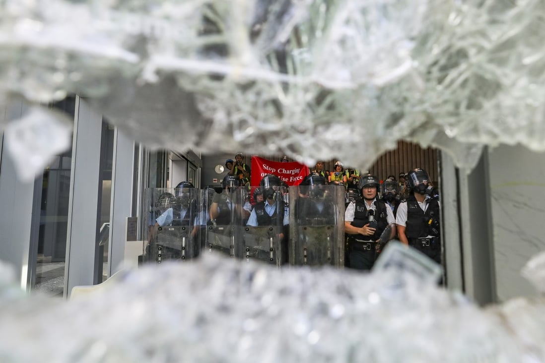 Riot police stand guard on Monday as protesters smash windows of the Legislative Council complex in Tamar. Photo: Sam Tsang