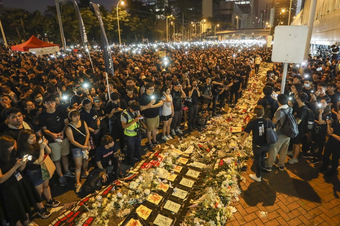 Protesters stand by flower bouquets on June 16 and offer prayers for a man who fell from Pacific Place mall in Admiralty and died while protesting against Hong Kong’s extradition law. Photo: Dickson Lee