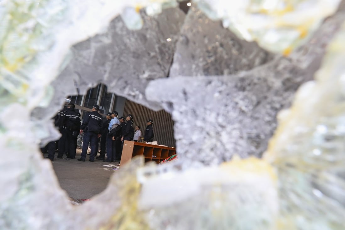 A group of Hong Kong police seen through broken glass after extradition bill protesters stormed the Legislative Council Chamber in Tamar. Photo: Felix Wong
