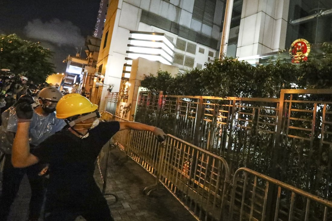 A protester takes aim at the national emblem outside Beijing’s liaison office in Hong Kong on Sunday. Photo: Felix Wong