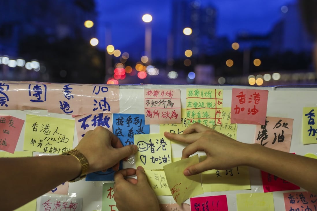 Two people attach a message ‘Hong Kong, add oil!’ to the Lennon Wall at Tai Wai. Photo: Sam Tsang