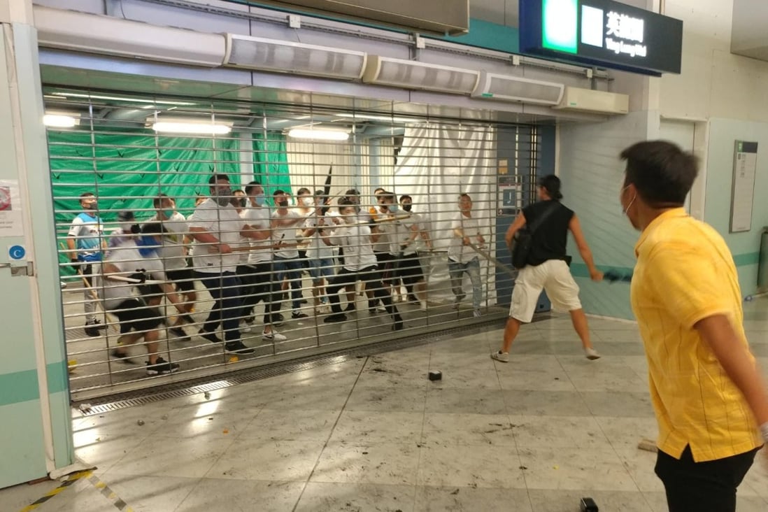 A mob of men in white T-shirts try to force open shutters at Yuen Long station. Photo: Handout