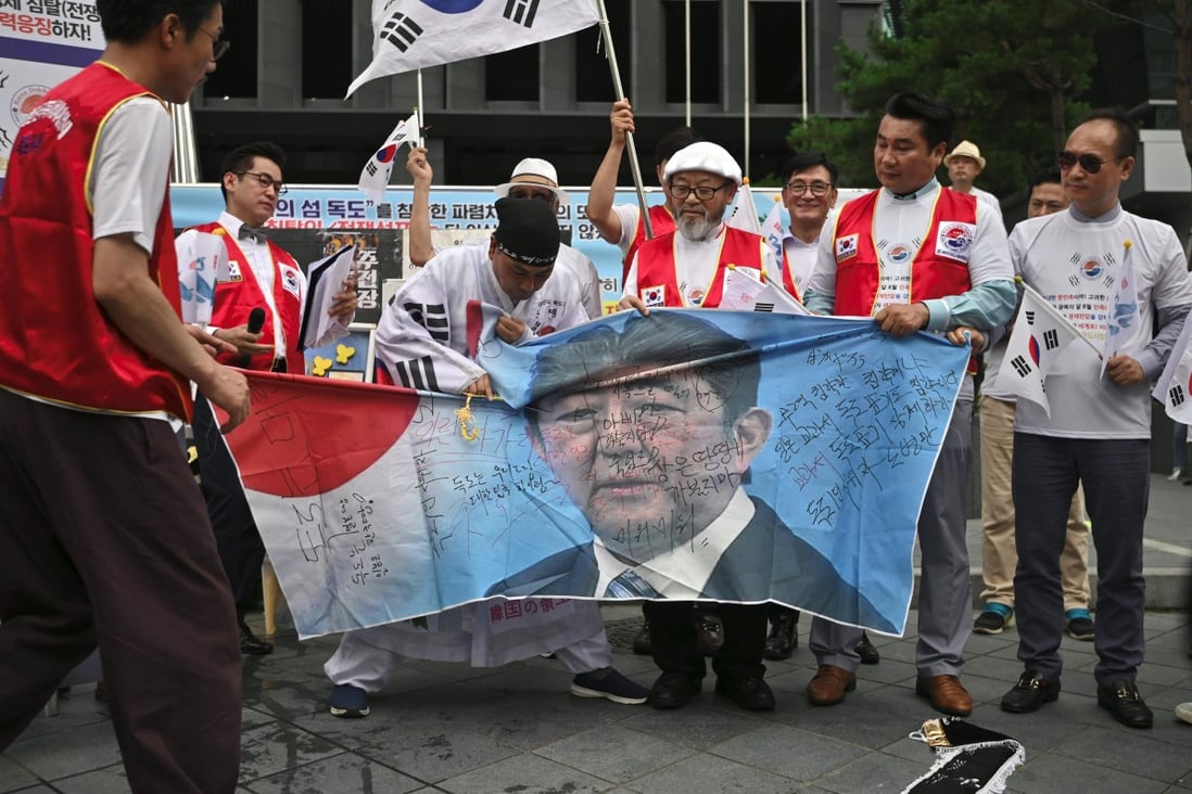 South Korean protesters cut a banner showing a picture of Japanese Prime Minister Shinzo Abe at a rally. Photo: AFP