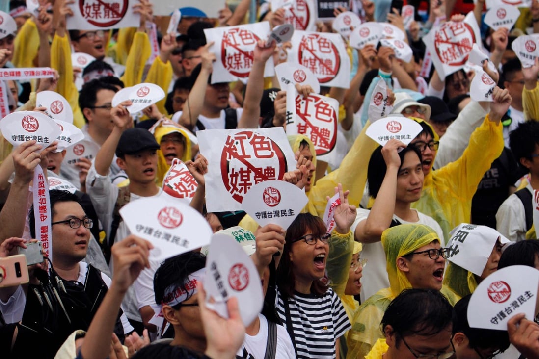 Protesters hold placards saying “reject red media” and “safeguard the nation’s democracy” during a rally against pro-China media in Taipei last month. Photo: AFP