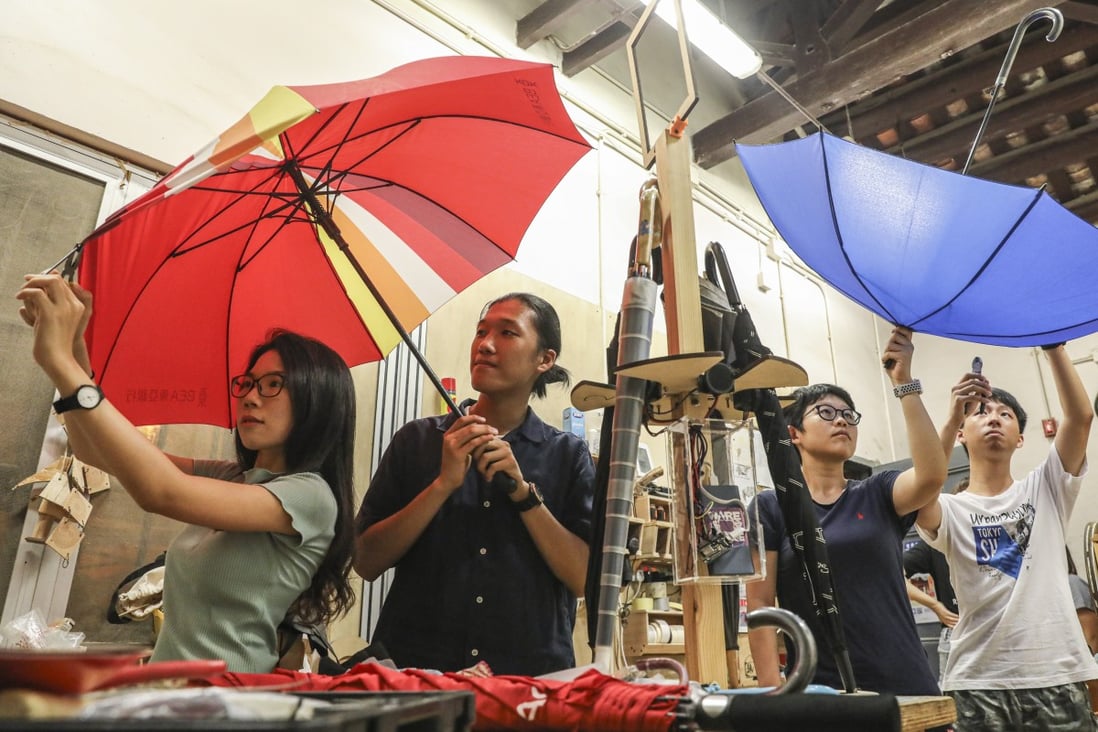 Winky Law and Jeffrey Kwong (left to right under red umbrella) repair a broken umbrella in a workshop at Aberdeen on July 17. Photo: Dickson Lee