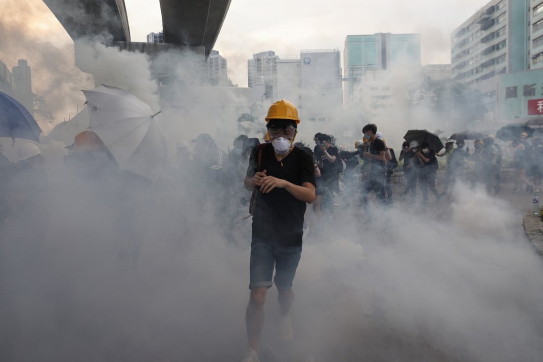 Protesters run through clouds of tear gas during clashes with police in Yuen Long. Photo: EPA-EFE