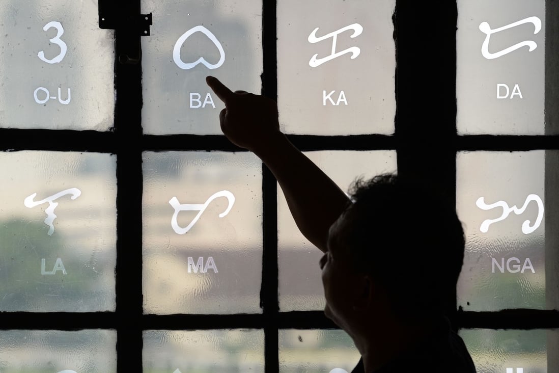 Researcher Leo Batoon pointing to a Baybayin character etched on a glass window at the National Museum in Manila. Photo: Agence France-Presse