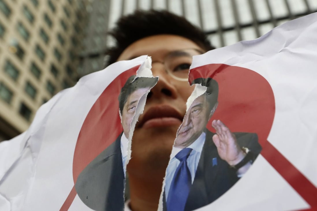 A protester in Seoul holds a defaced image of Japanese Prime Minister Shinzo Abe during a rally denouncing the Japanese government on July 17. Photo: AP
