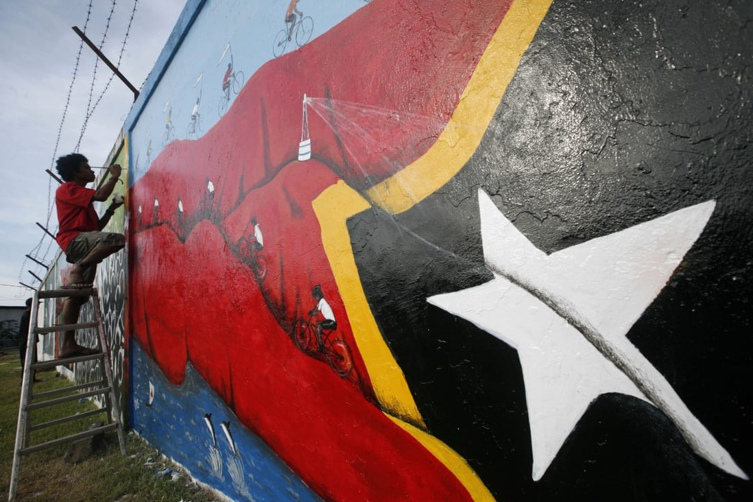 A man in East Timor puts the finishing touches to a mural in the capital Dili. Photo: AP