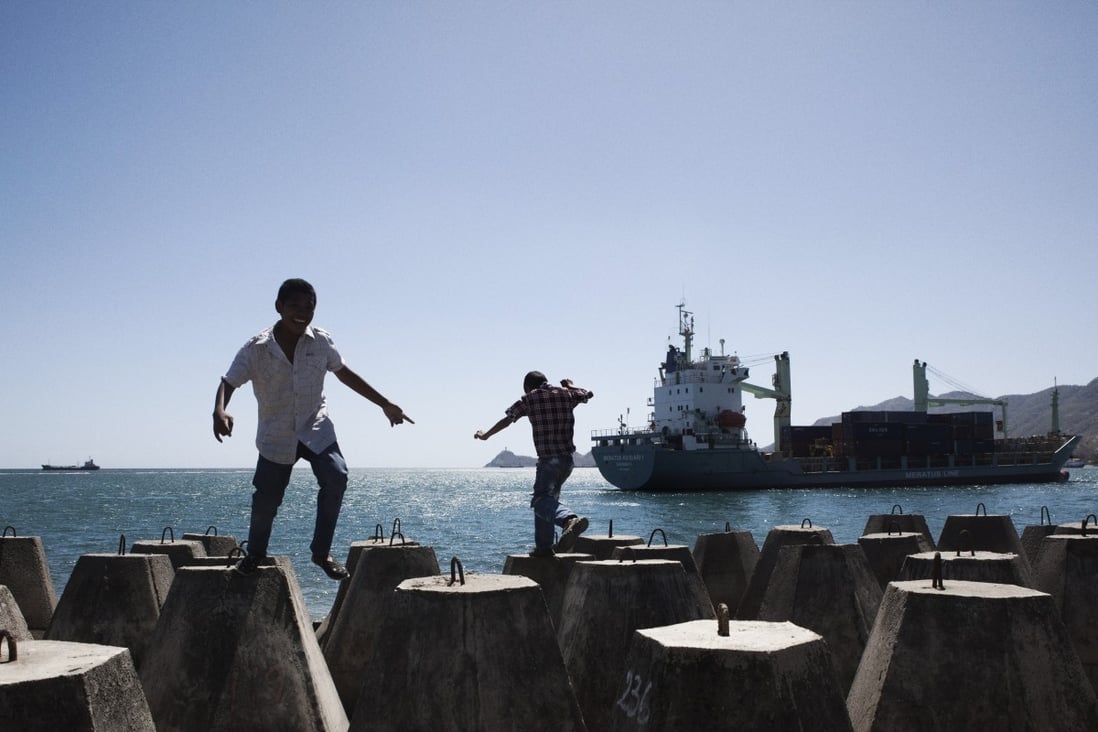 Boys play near a harbour in Dili, East Timor, as a container ship sails into port. File photo