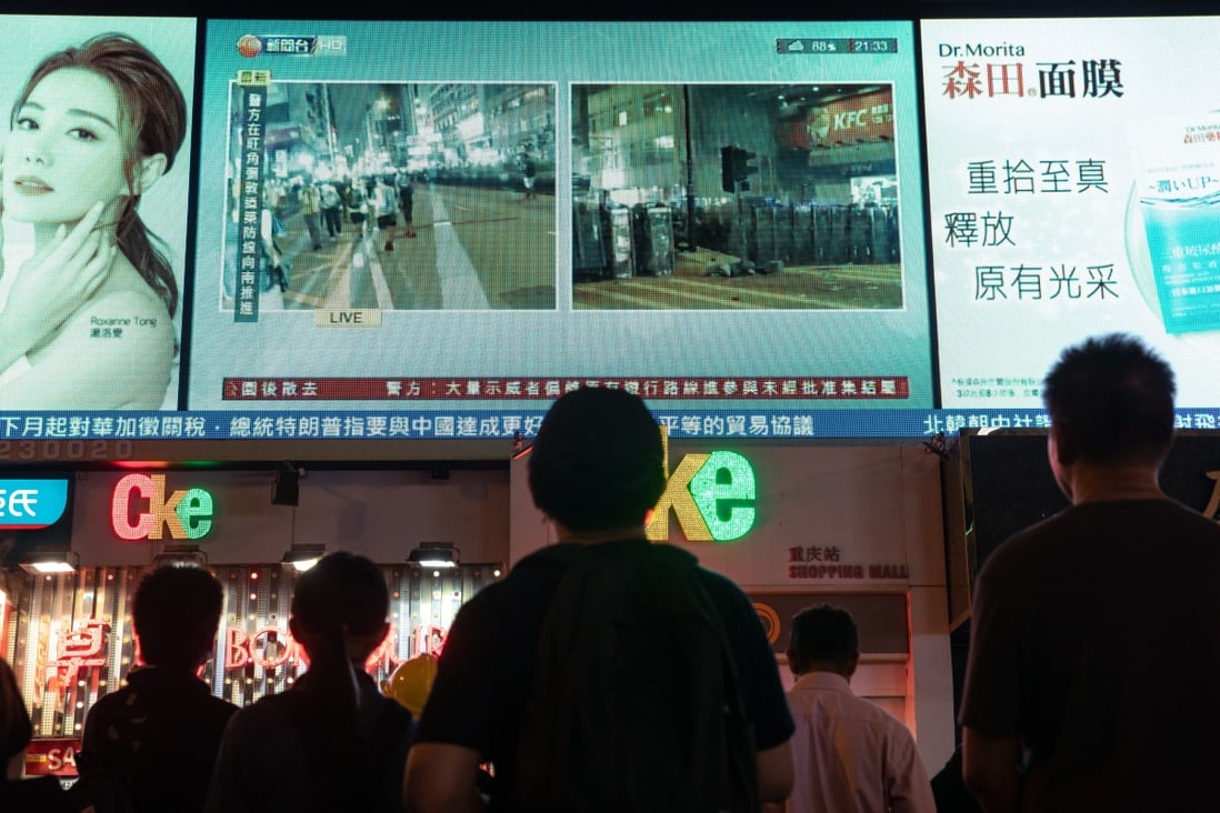 People in Tsim Sha Tsui watch a live television broadcast of protests in the city on August 3. Photo: Bloomberg
