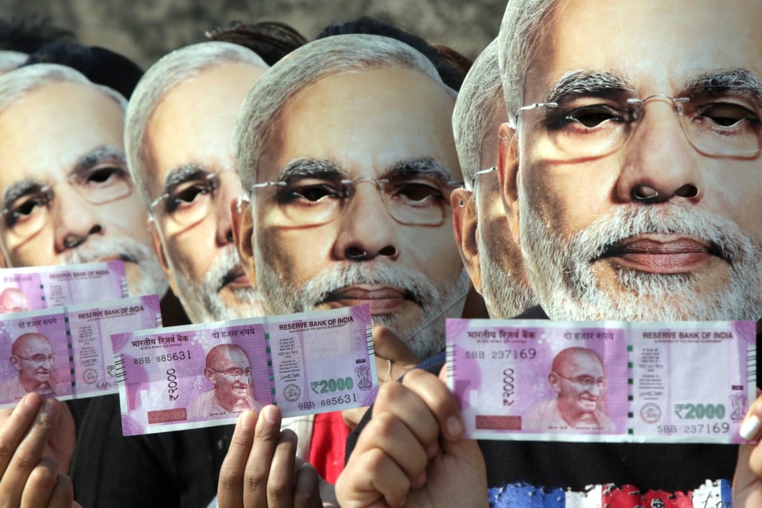 Indian girls wear masks depicting Indian Prime Minister Narendra Modi and hold up new currency notes in November, 2016. Photo: EPA