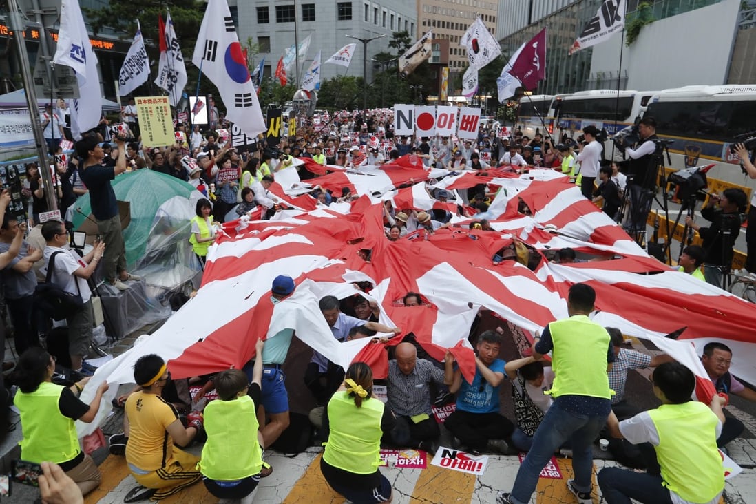 Protesters tear up a Japanese rising sun flag during a rally in front of the Japanese embassy in Seoul in July. Photo: AP