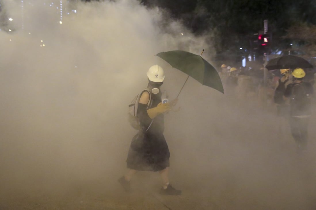 A protester walks through billowing tear gas outside a train station in Wong Tai Sin on August 4, 2019. Photo: Sam Tsang