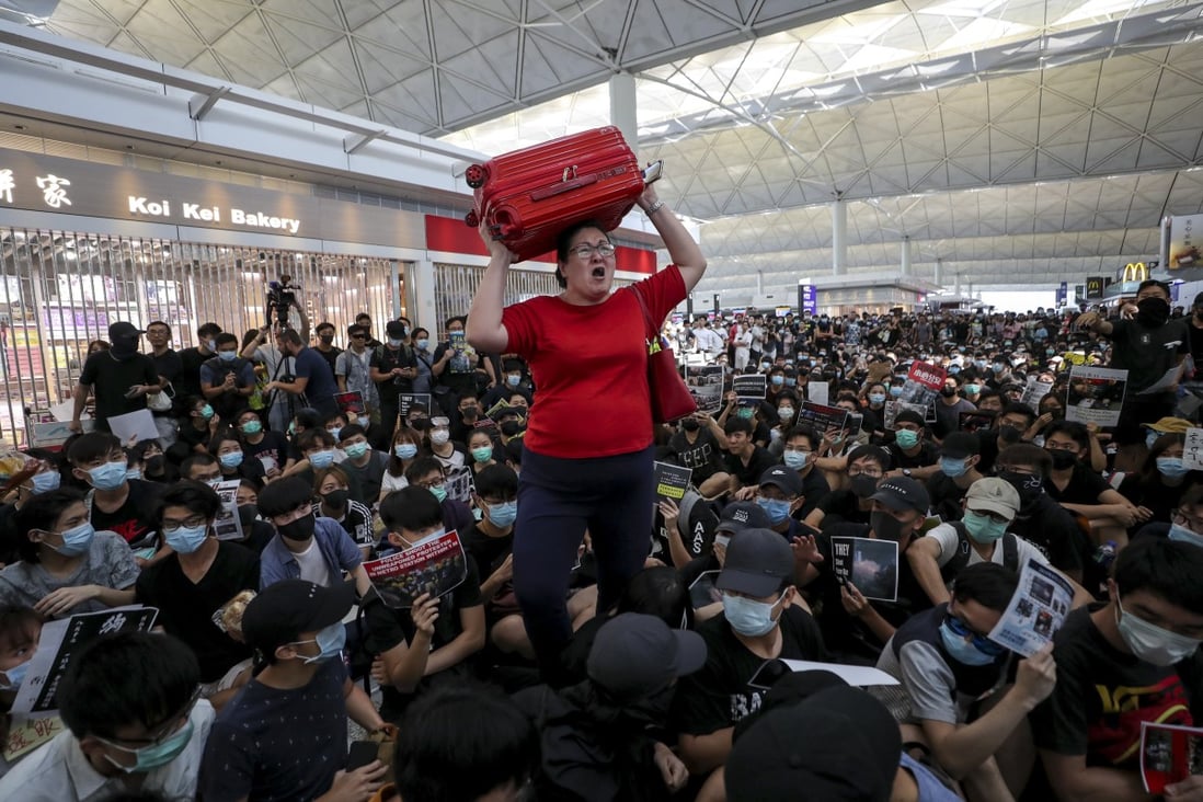 A passenger furious at the disruption tries to get through the mass of protesters in her path at Hong Kong airport’s departures. Photo: Sam Tsang