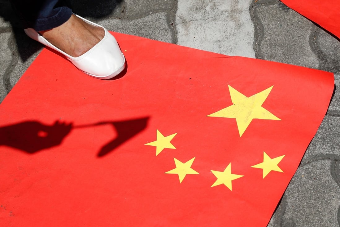 An activist outside the Department of Foreign Affairs in Manila steps on a paper Chinese flag during a protest against the sinking of a fishing boat. Photo: EPA