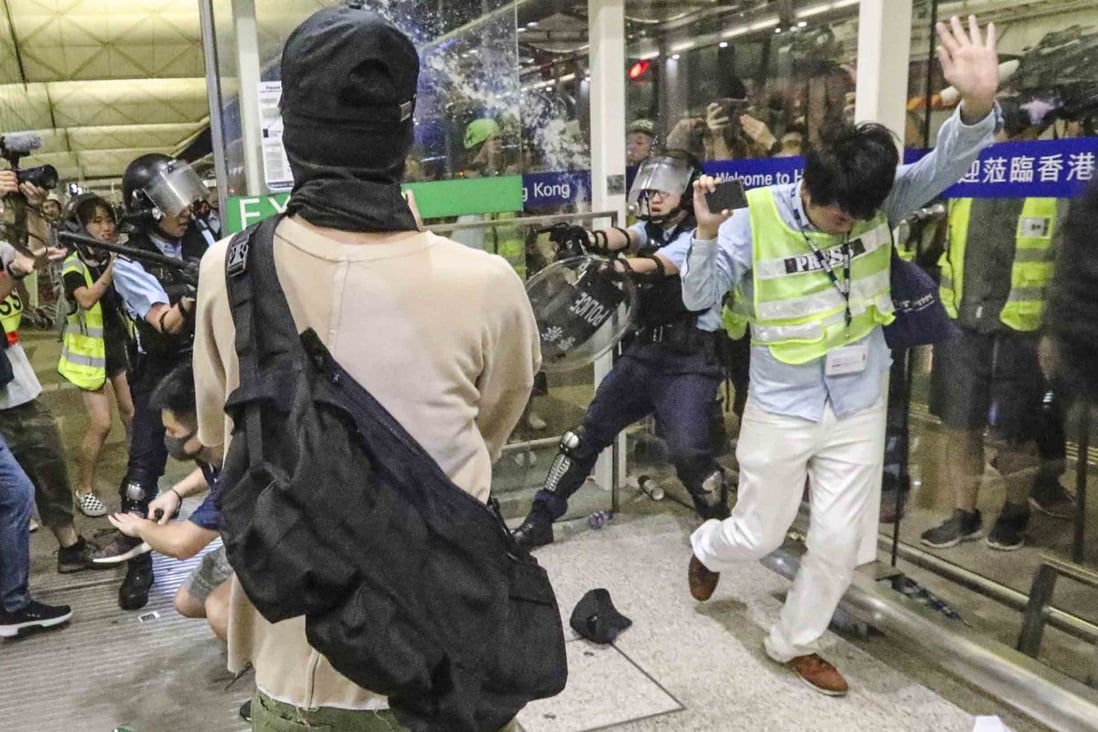 A police officer (right) draws and points his gun at the airport. Photo: Felix Wong