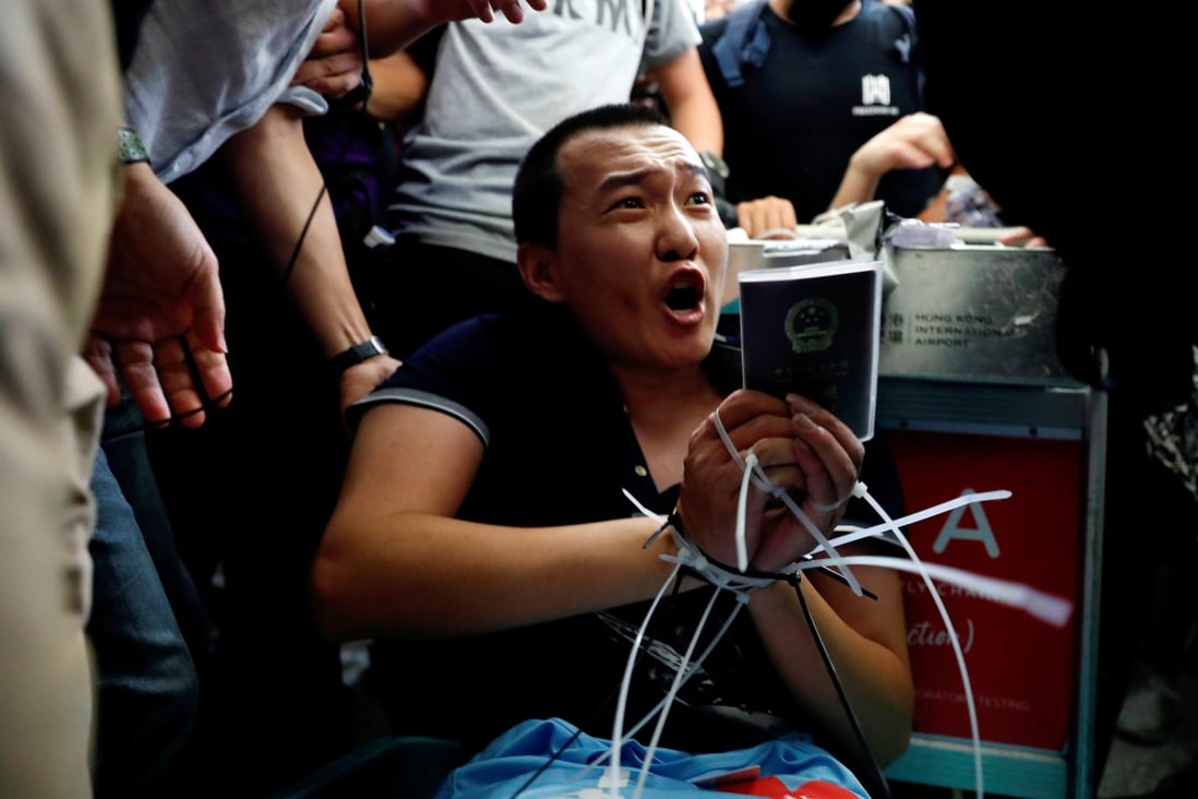 Fu Guohao is surrounded by protesters after having his hands tied together at Hong Kong International Airport. Photo: Reuters