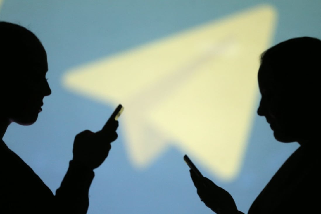 Silhouettes of smartphone users are seen next to a projected logo of messaging app Telegram, which has seen installations surge in Hong Kong. Photo: Reuters
