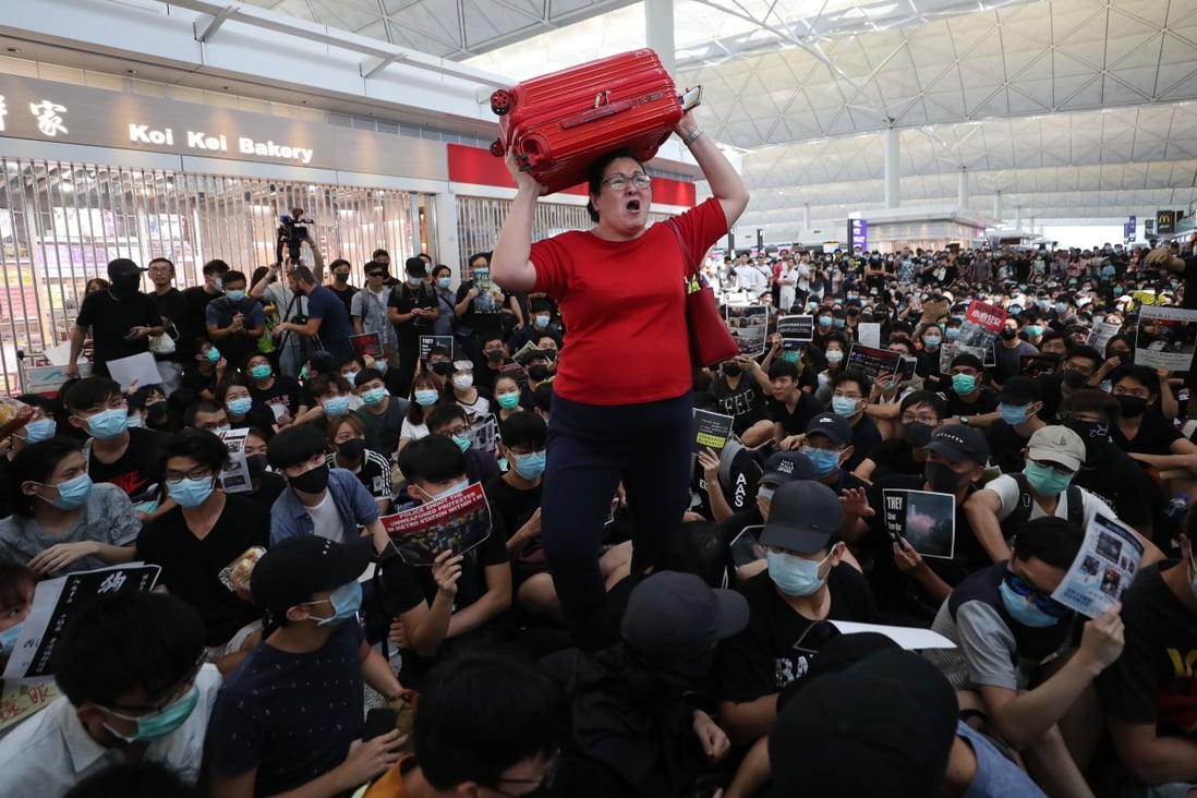 A woman attempts to navigate through a crowd of anti-government protesters inside the departure hall of Hong Kong International Airport, on Monday. The protests forced the cancellation of hundreds of flights over two days. Photo: Sam Tsang