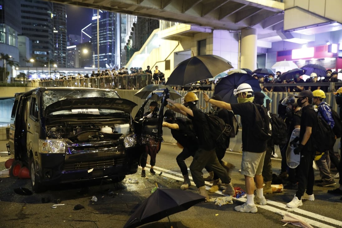 Protesters attack a van that apparently tried to drive at them near a blocked road in Hong Kong last month. Chinese state media has ramped up its propaganda against demonstrators in the city. Photo: AP
