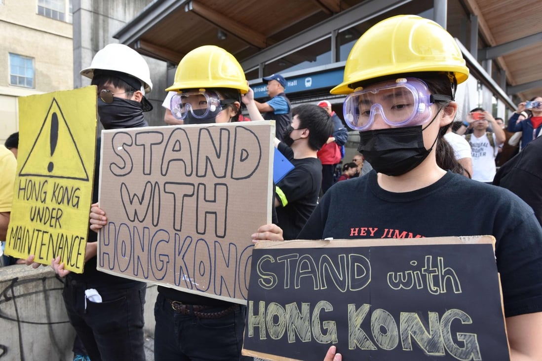 Pro-Hong Kong supporters hold signs during a rally at the Broadway-City Hall SkyTrain Station in Vancouver. Photo: AFP