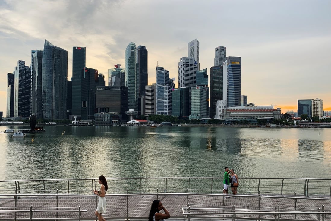 Passers-by hold their mobile phones as people take a selfie photo using a smartphone, with Singapore's central business district skyline, in Singapore, May 10, 2019. Photo: Reuters