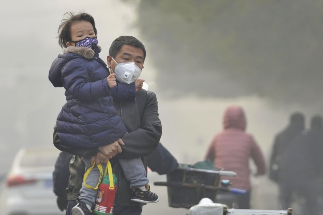A man and his daughter wear face masks to protest themselves from air pollution in Beijing. Photo: Kyodo