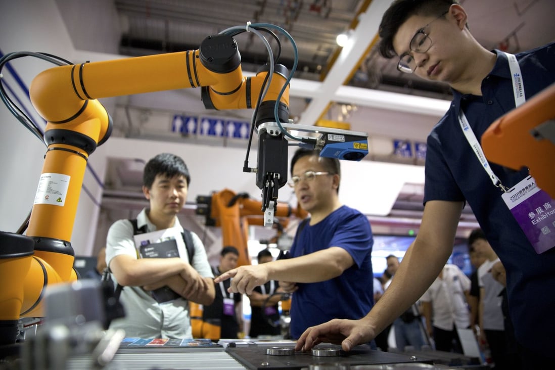 Visitors look at a robotic arm from Chinese company Aubo Robotics at the World Robot Conference in Beijing on August 15, 2018. Photo: AP