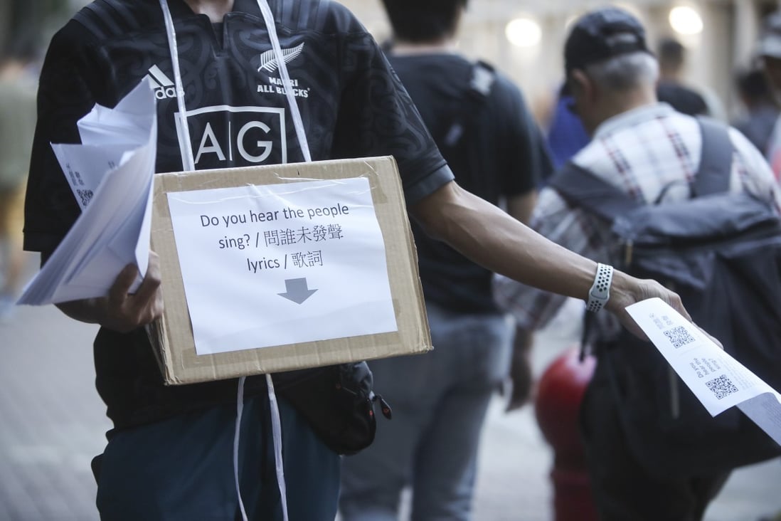 A protester handing out the lyrics to ‘Do You Hear The People Sing?’ ahead of the football match between Manchester City and Kitchee at Hong Kong Stadium on July 24. Photo: Winson Wong
