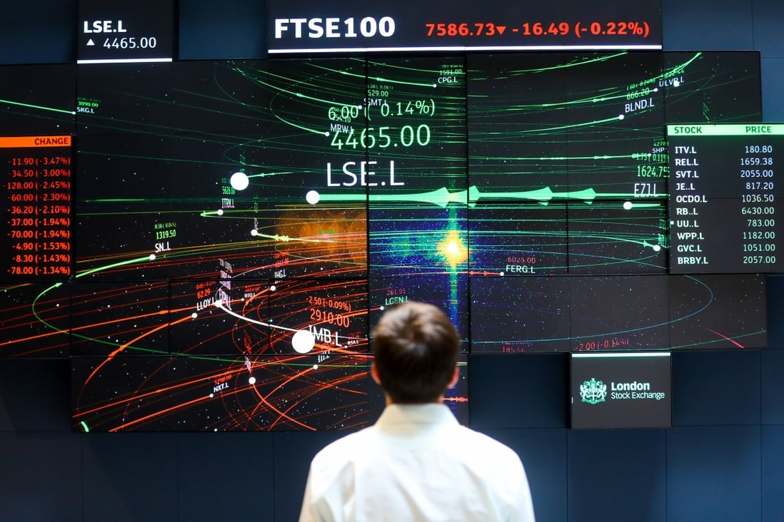 An employee looks at information for the FTSE 100 share price information in the atrium of the London Stock Exchange Group Plc's offices on July 6, 2018. Photo: Bloomberg