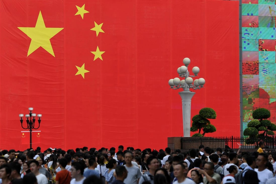 People walk in front of a giant Chinese flag ahead of the 70th anniversary of the People's Republic China in Chongqing, China September 13, 2019. Photo: Reuters
