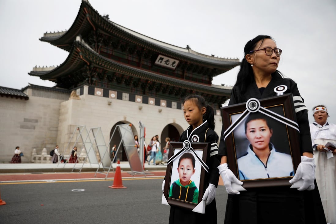 A North Korean refugee and her daughter hold portraits of a fellow refugee and her son, during their funeral in Seoul on September 21. Photo: Reuters