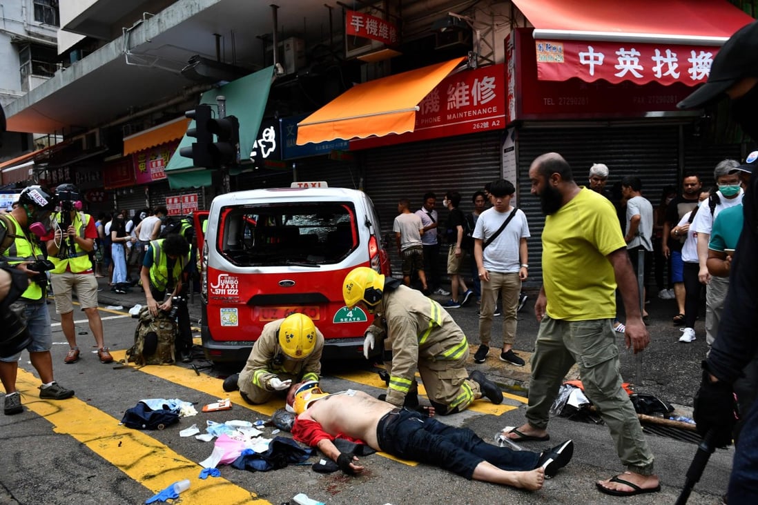 Brutalised taxi driver Henry Cheng receives treatment at the scene after the taxi he was driving ploughed into a crowd, seriously injuring a woman. Photo: AFP