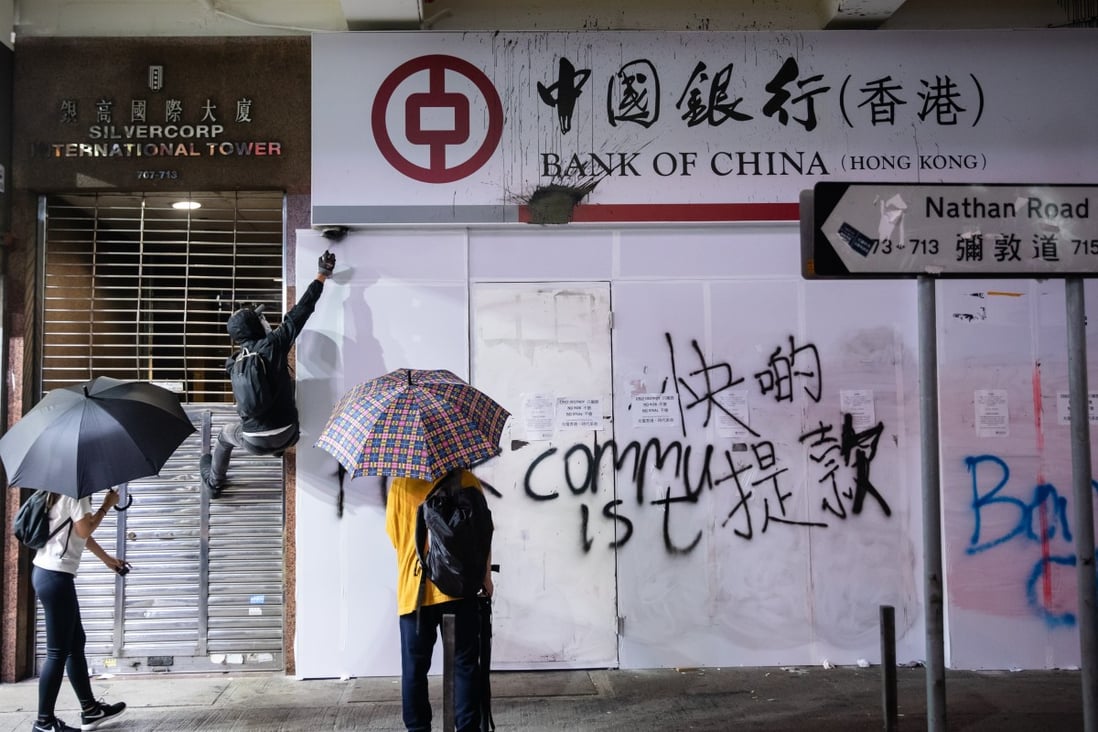 Demonstrators spray paint a security camera at a Mong Kok branch of the Bank of China. Photo: Bloomberg