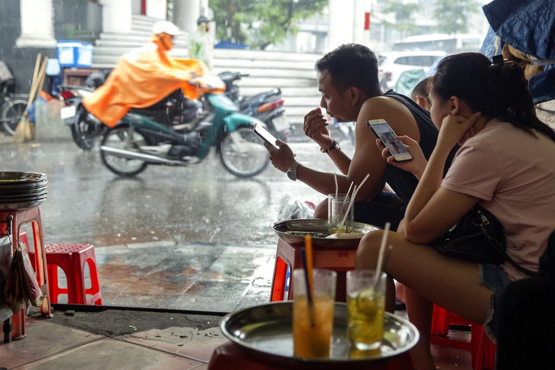 People use smartphones as they sit and drink tea by the roadside in Hanoi, Vietnam, which plans to become a cashless economy by 2027. Photo: Bloomberg