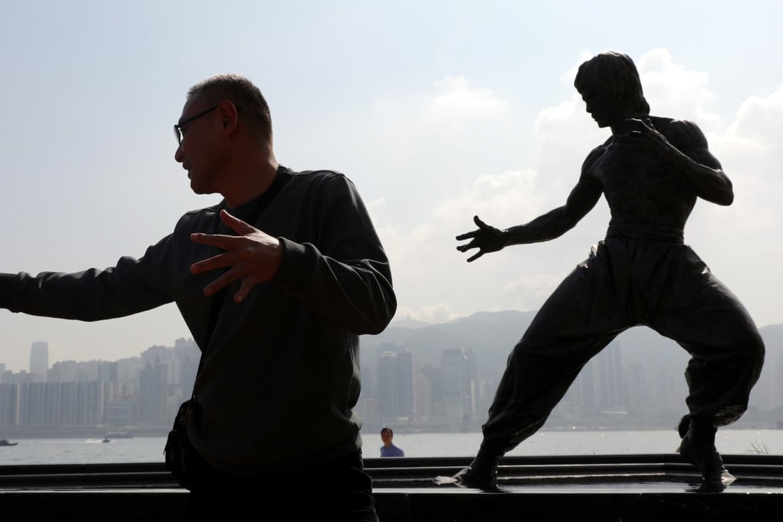 A tourist poses for a photo with the statue of Bruce Lee at the Avenue of Stars in Tsim Sha Tsui on the first day after its reopening. Photo: Sam Tsang