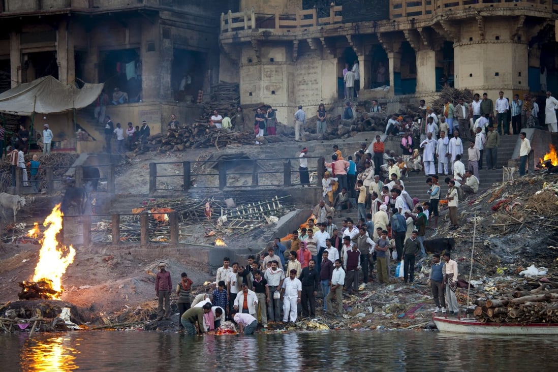 A traditional Hindu cremation takes place on a funeral pyre at Manikarnika Ghat beside the River Ganges in the Indian holy city of Kashi, also known as Varanasi or Benares. Photo: Robert Harding