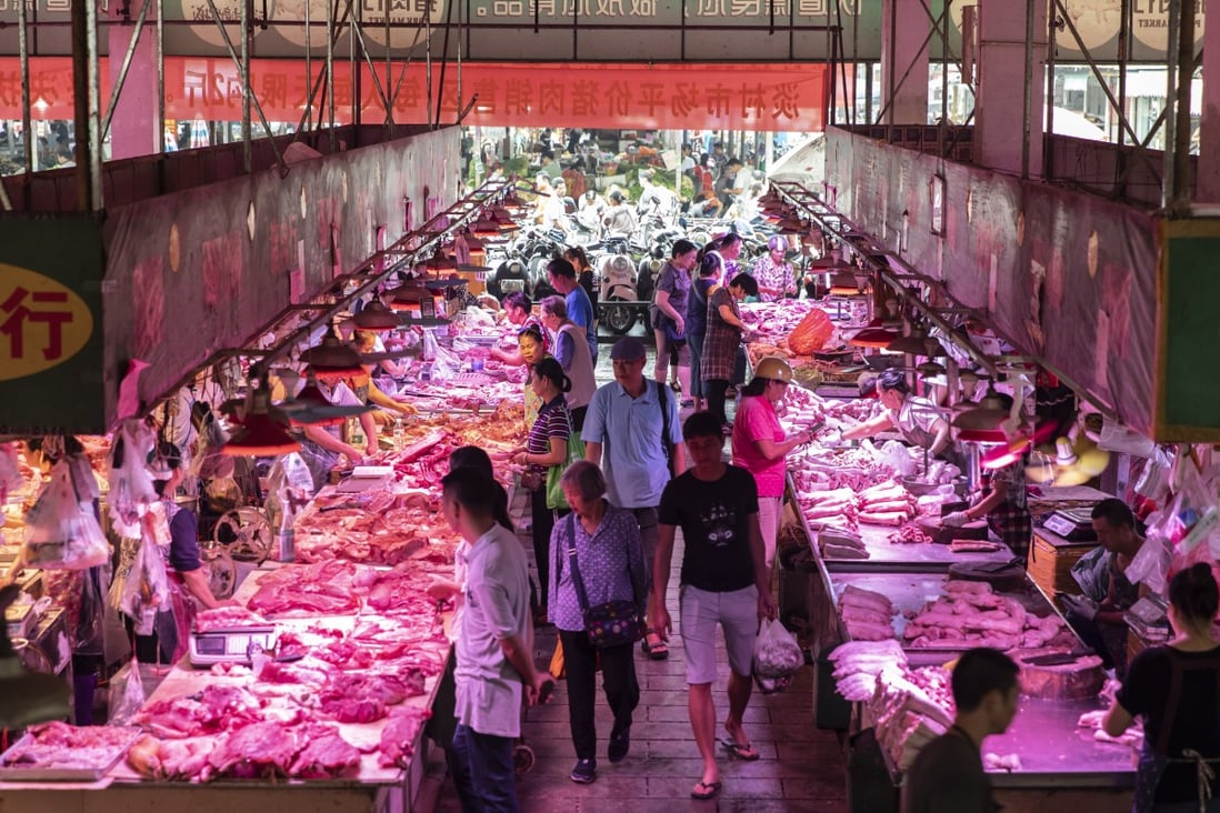 Customers walk past pork stalls at the Dancun Market in Nanning, Guangxi province. Photo: Bloomberg