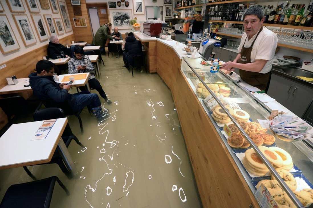 People sit in a flooded bar amid rising water levels in Venice. Photo: EPA