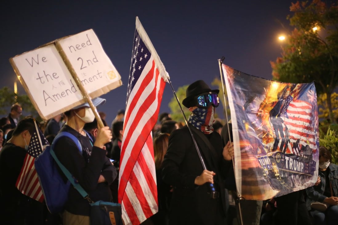 Demonstrators hold up signs and US flags during a rally in Central district of Hong Kong. Photo: Bloomberg