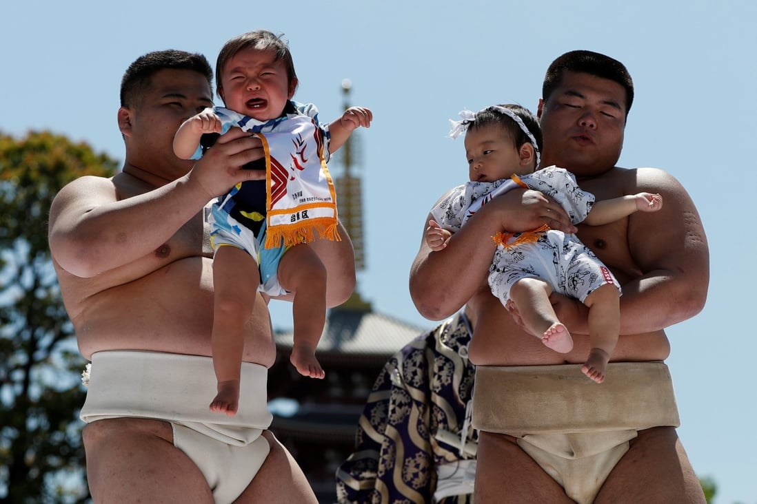 Babies cry as they are held up by amateur sumo wrestlers at a temple in Tokyo in April 2018. Photo: Reuters