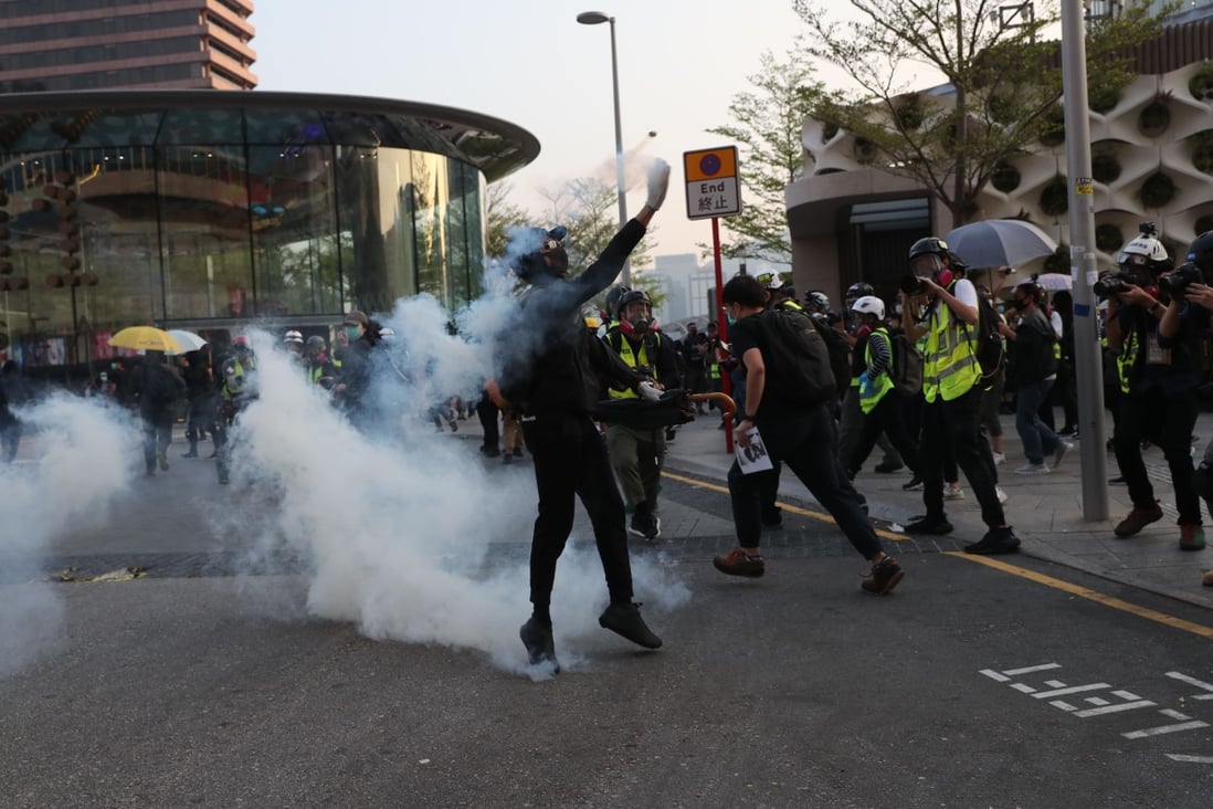 A masked protester throws back a round of tear gas. Photo: Sam Tsang