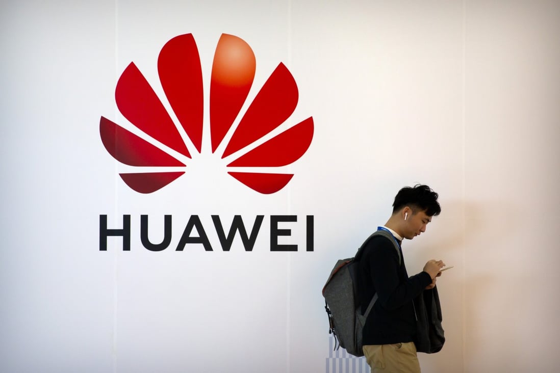 A man uses his smartphone as he stands near a Huawei logo at the PT Expo in Beijing in October. Photo: AP