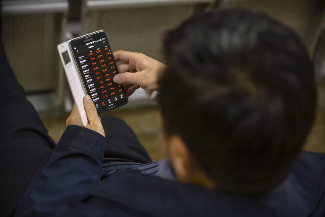 A Chinese investor uses a smartphone to monitors stock prices at a brokerage house in Beijing. Photo: Associated Press