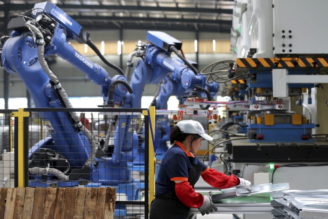 A worker assembles air conditioner's components next to the robot arms at a factory in Suixi county in central China's Anhui province in 2018. Photo: AP
