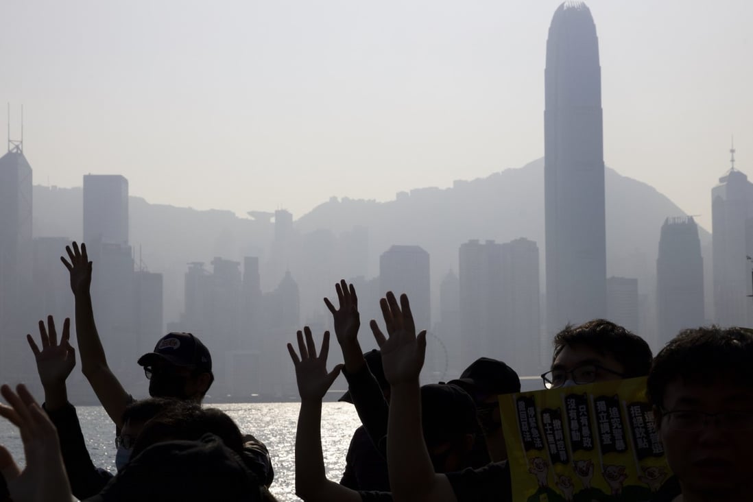 Pro-democracy protesters raise their hands to symbolise the five demands of their movement, with the Hong Kong Island skyline behind them. Photo: AP