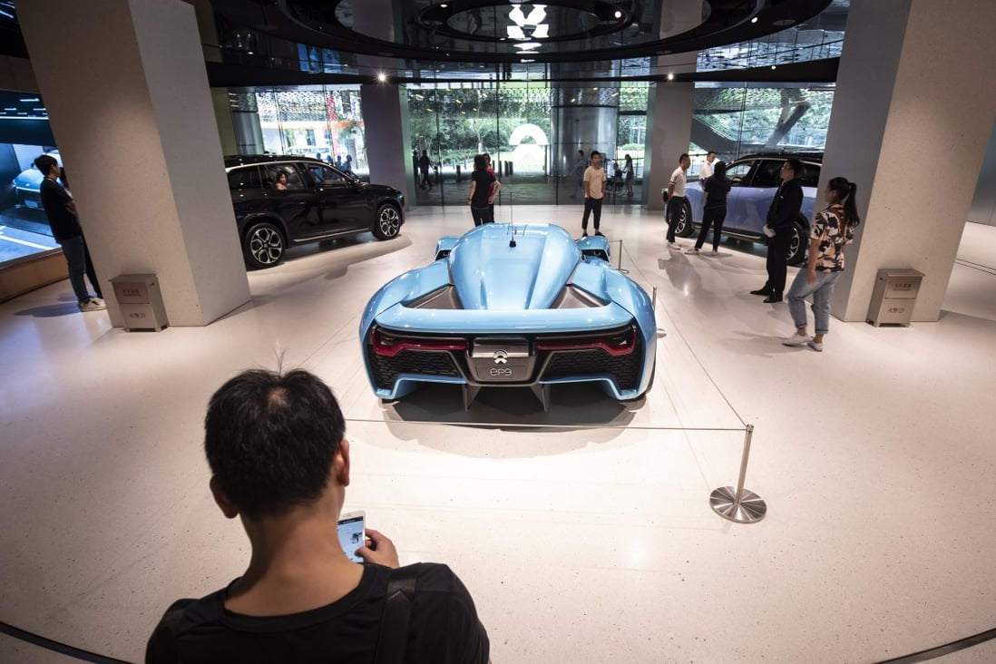Customers look on as the EP9 electric sports car stands on display inside the NIO House showroom at the Shanghai Tower in Shanghai on September 14, 2018. The company now plans to set up much smaller stores called NIO Spaces. Photo: Bloomberg
